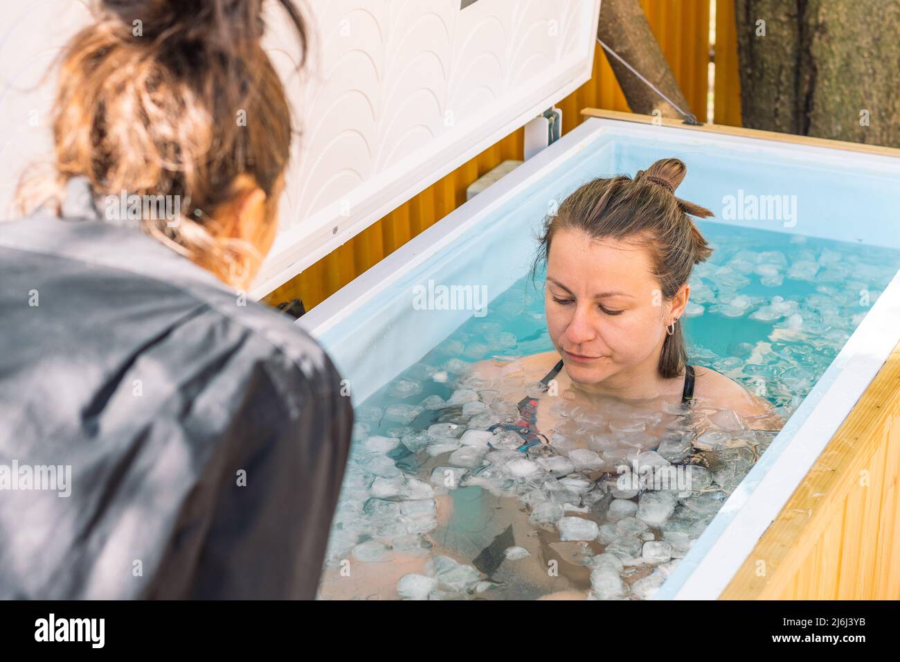 Girl or woman bathing in the cold water among ice cubes with instructor
