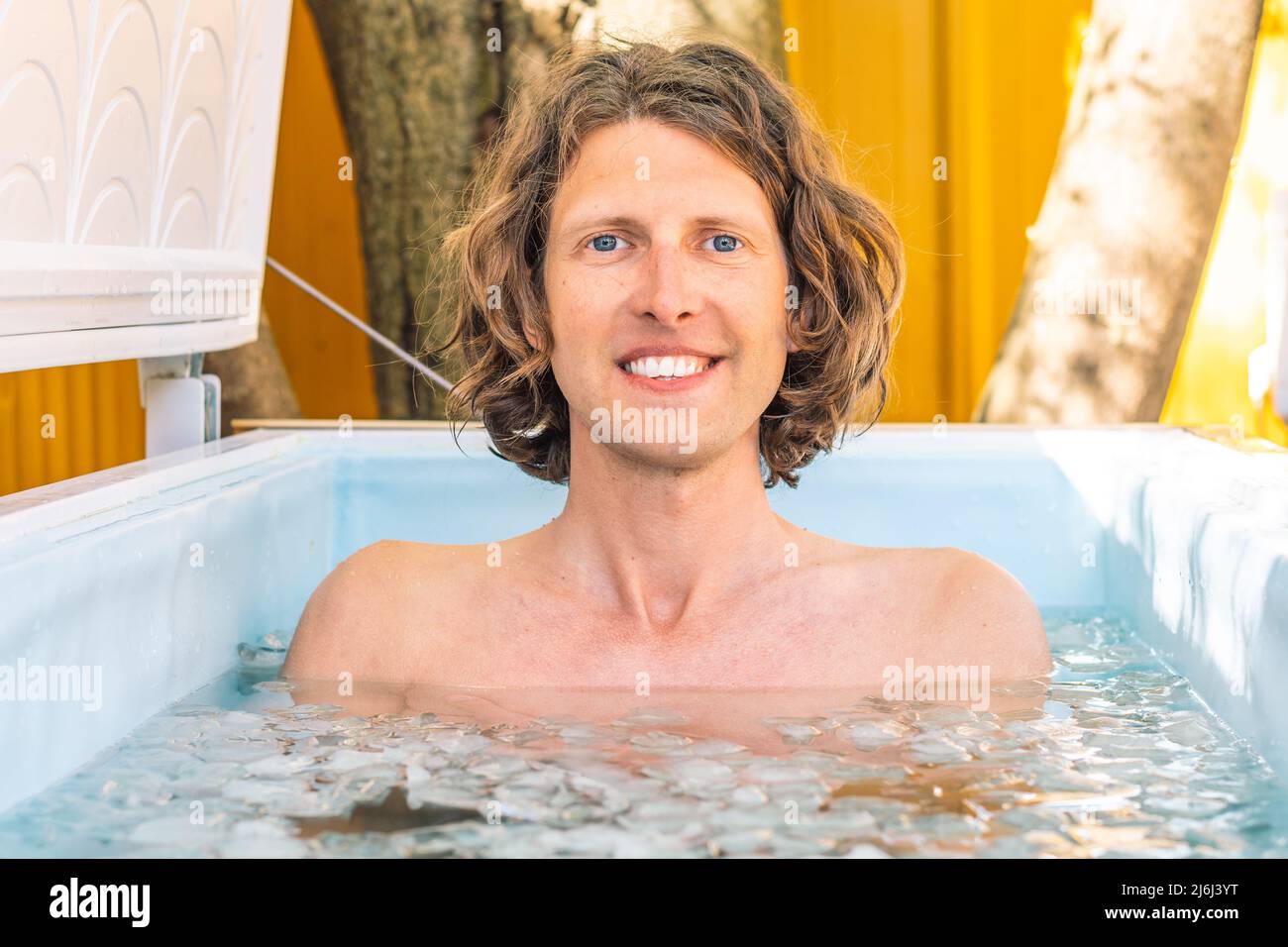 Boy or man smiling and bathing in the cold water among ice cubes. Wim