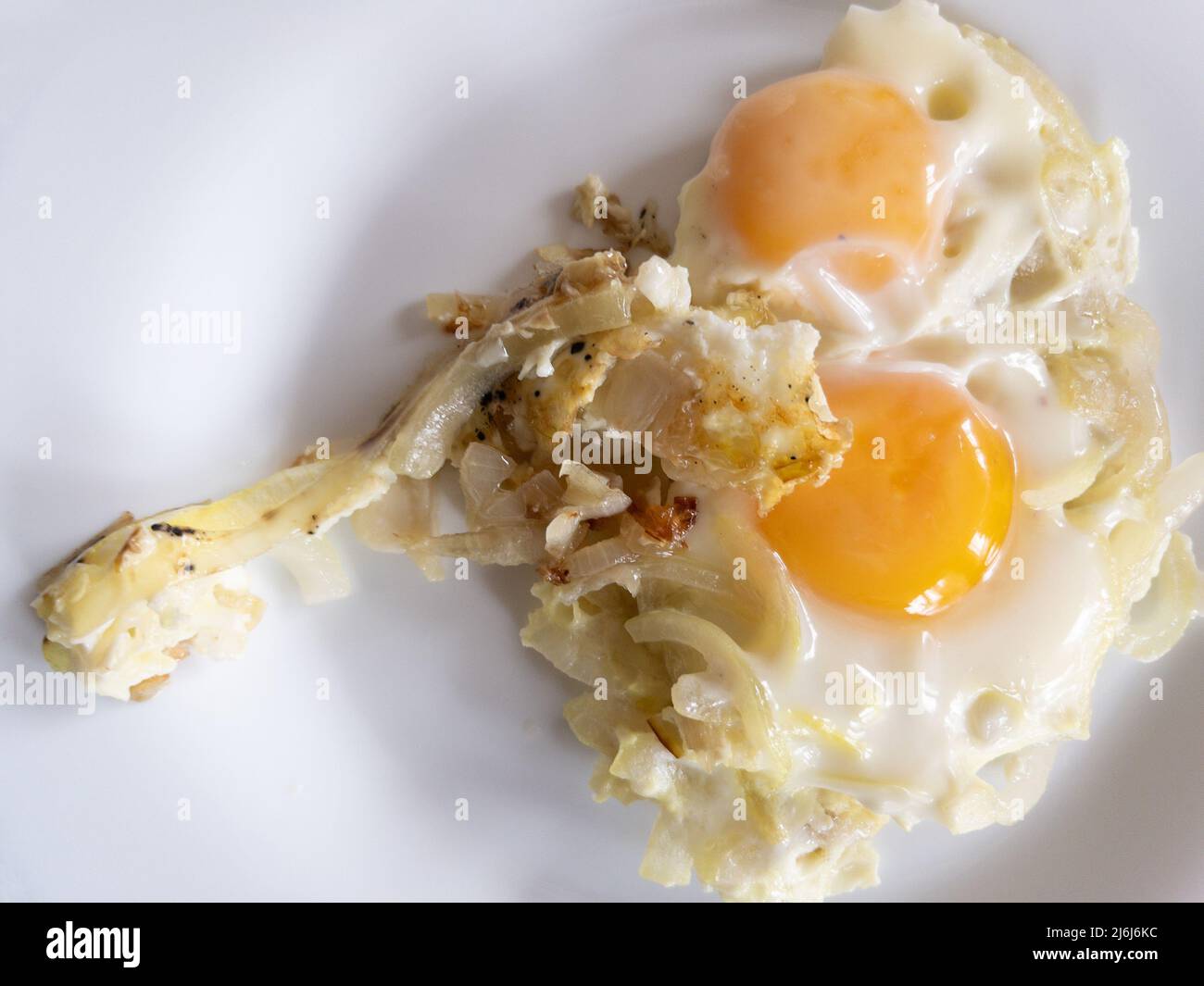 Top view on fryingwhite plate with twoeggs fried on roasted onionthat people in  Ukraine cook often Stock Photo