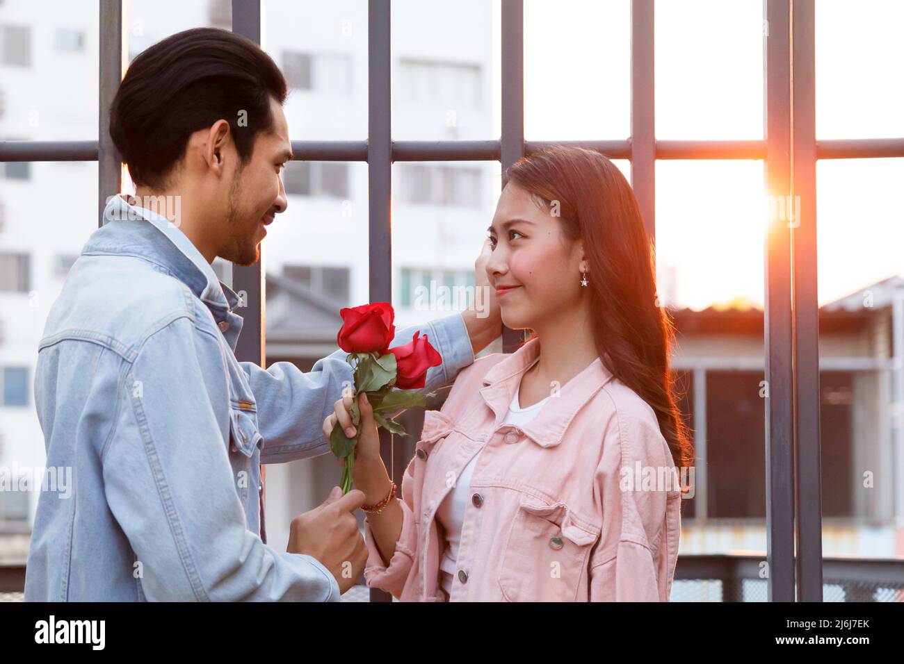 young happy couple love and romantic at first date relationship. asian teenage woman surprise and smiling at boyfriend gives red rose flowers at dinne Stock Photo