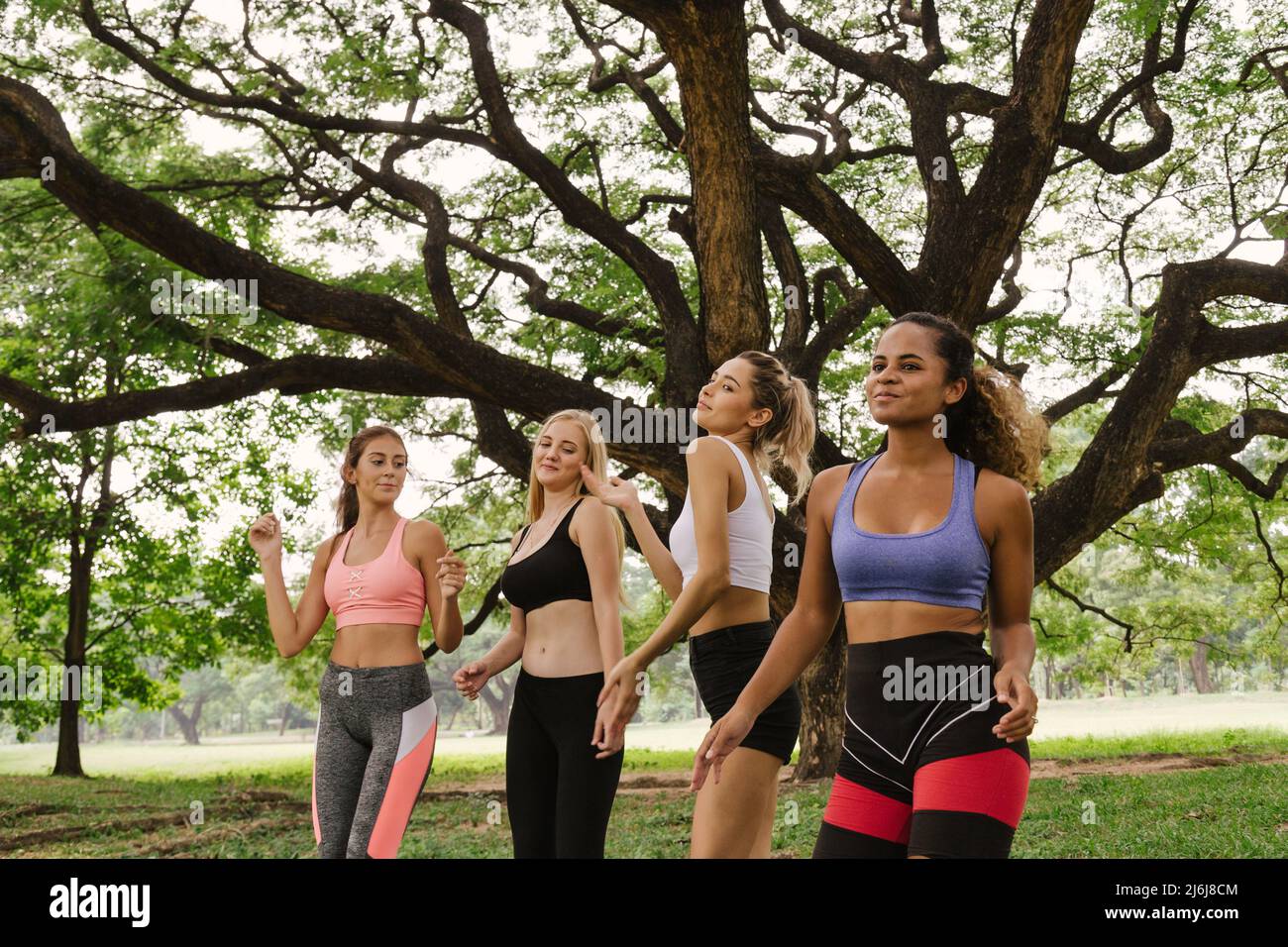 happy young multiethnic women teenager friend group relaxing and dancing after exercise in the park at weekend morning. young people lifestyle concept Stock Photo