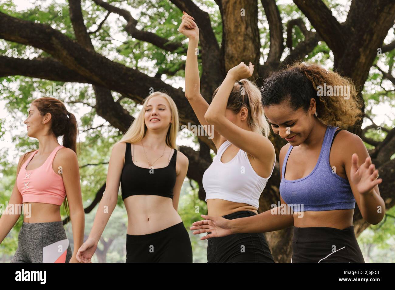 happy young multiethnic women teenager friend group relaxing and dancing after exercise in the park at weekend morning. young people lifestyle concept Stock Photo