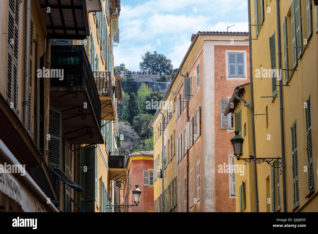 A narrow street in Nice Old Town, looking towards Castle Hill and the Waterfall above the town. Stock Photo