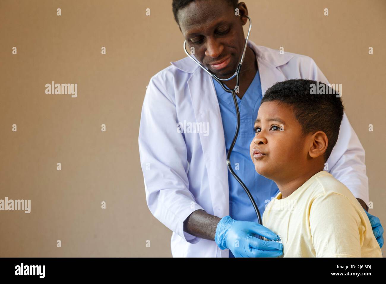african american man pediatrician doctor using stethoscope to examining little boy from sickness in the office at the hospital. medical and healthy li Stock Photo