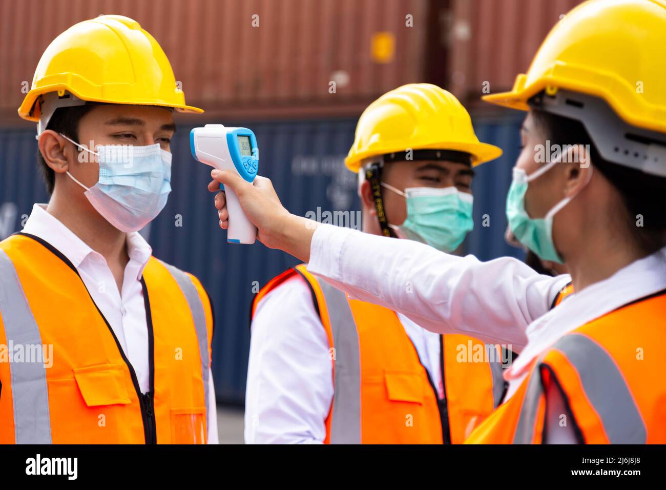 asian man workers wearing face mask checking fever by digital thermometer before entering the work for protecting from covid, covid-19 or coronavirus Stock Photo