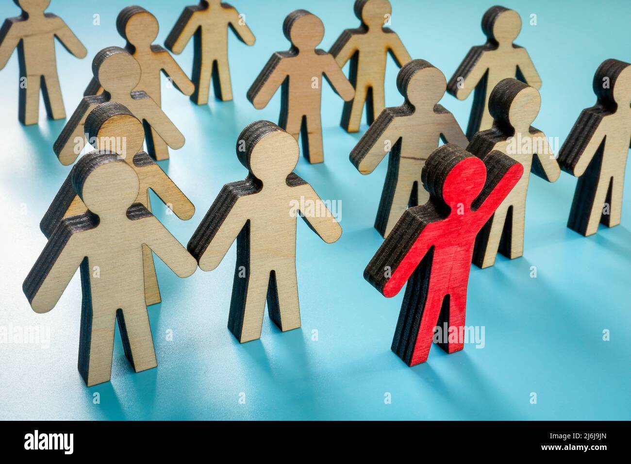 Crowd from figurines and red one as a leader. Stock Photo