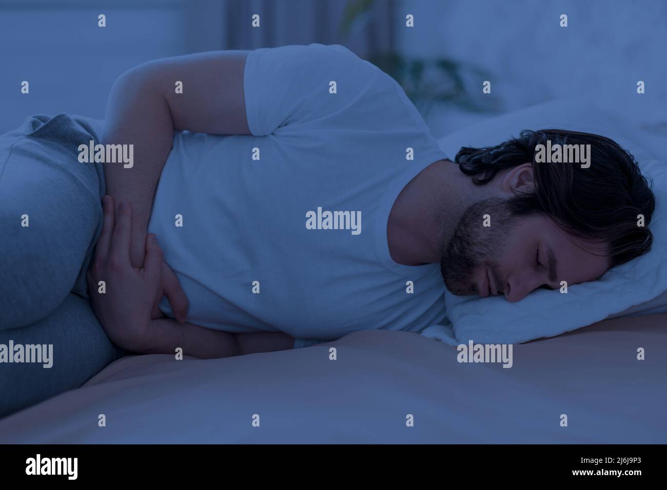 Sick man suffering from stomach cramps at night Stock Photo Alamy