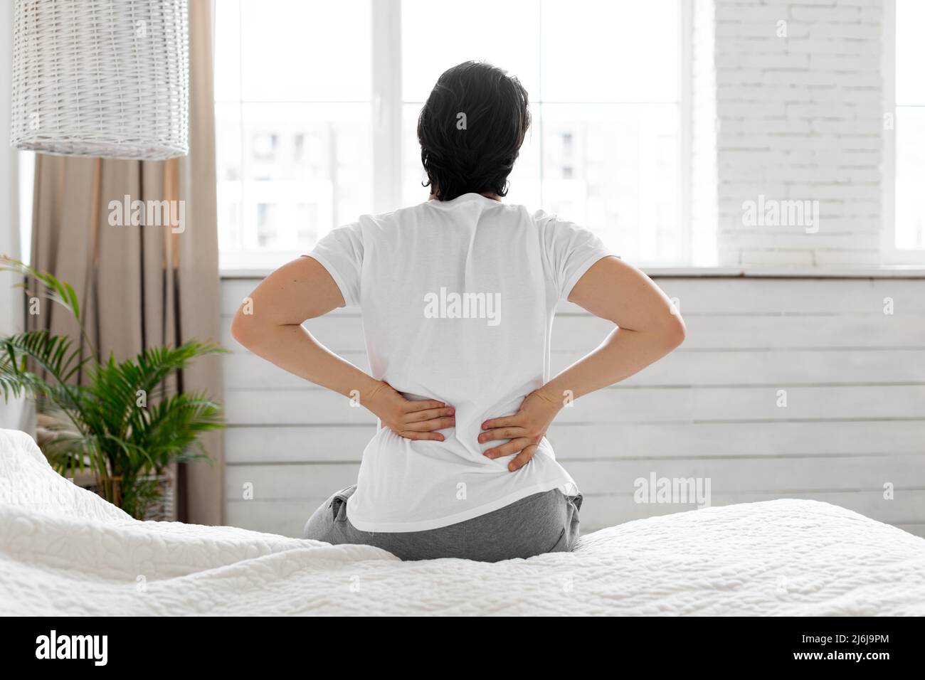 Man suffering from back pain at home in bedroom Stock Photo - Alamy
