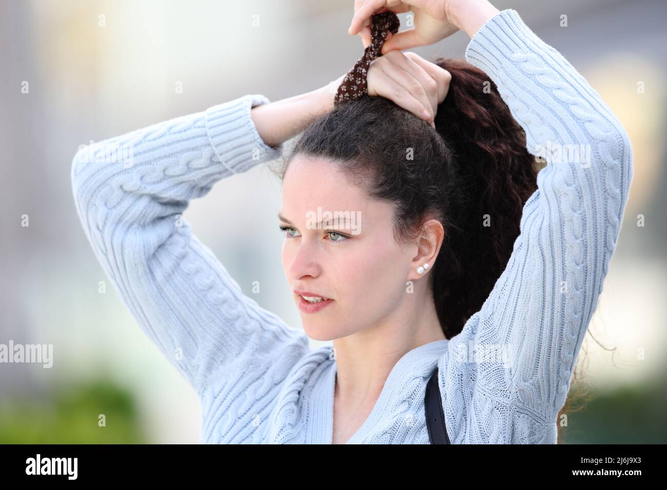 Casual woman doing ponytail walking in the street Stock Photo