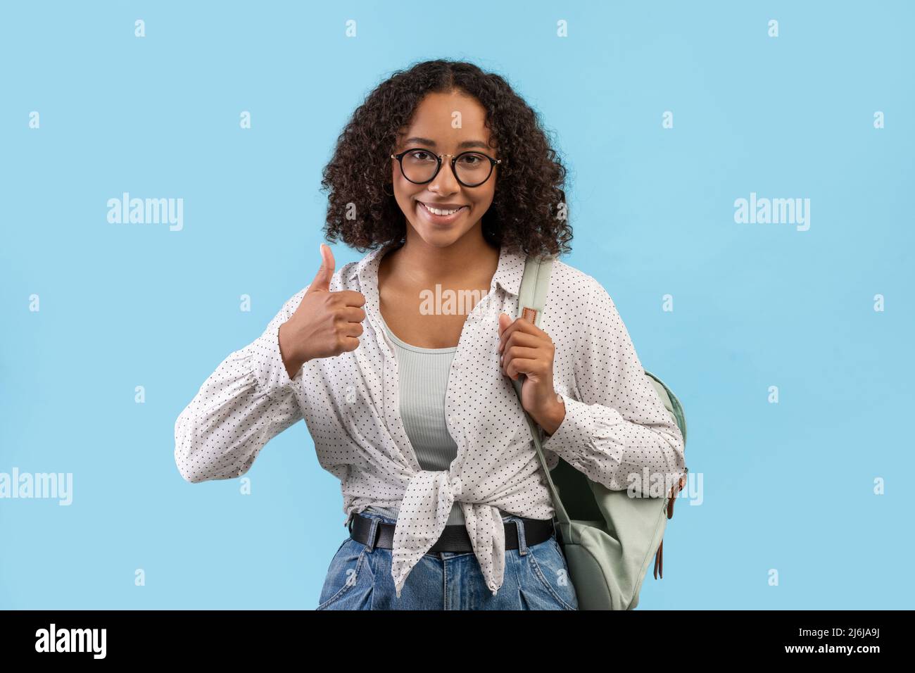 Cheerful African American female student with backpack showing thumb up ...