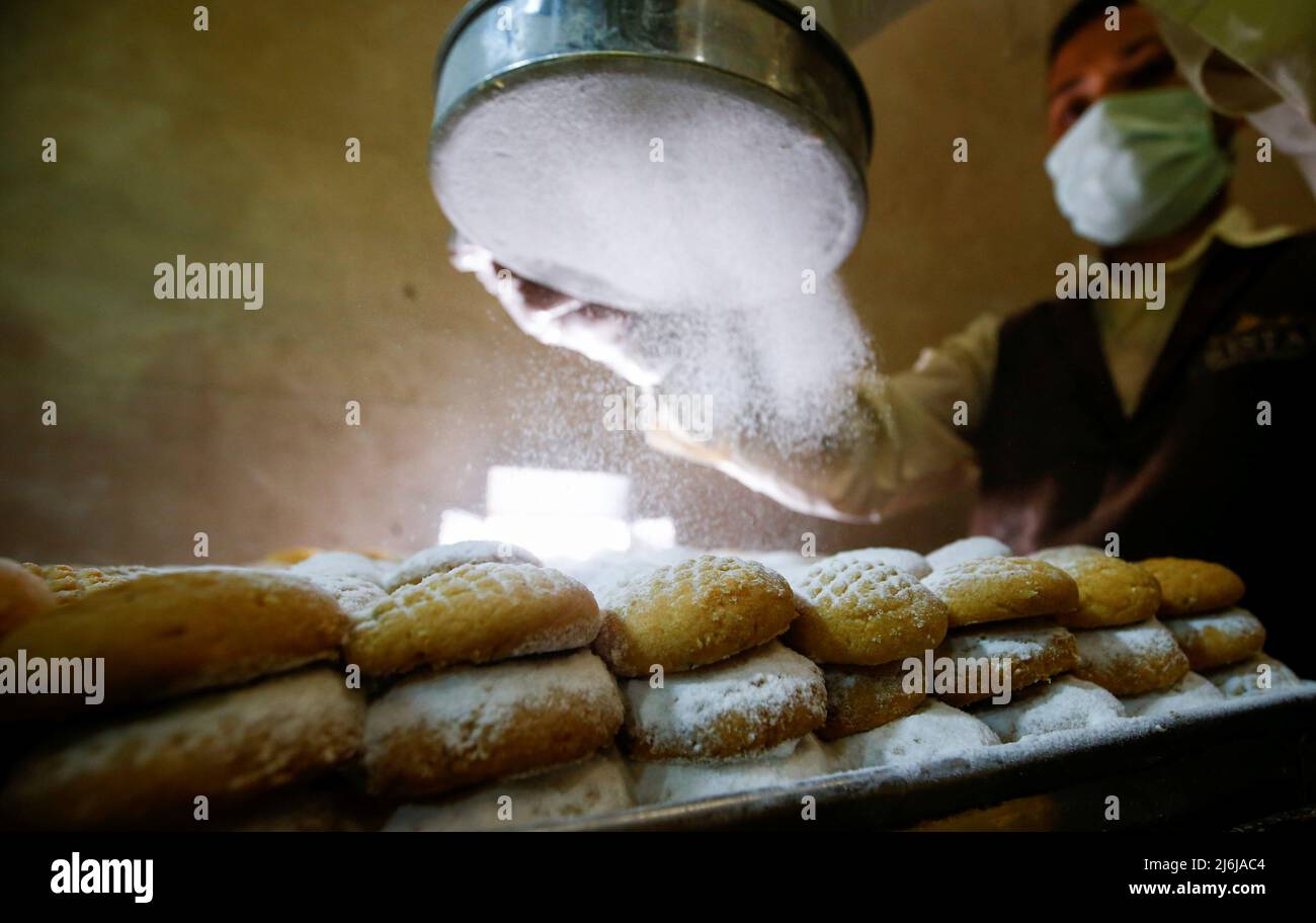 An Egyptian worker puts sugar on traditional sweet cookies "Kahk", as part of the celebrations