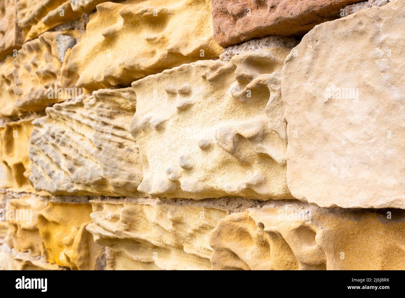 Old sandstone wall showing severe erosion and weathering, England UK Stock Photo