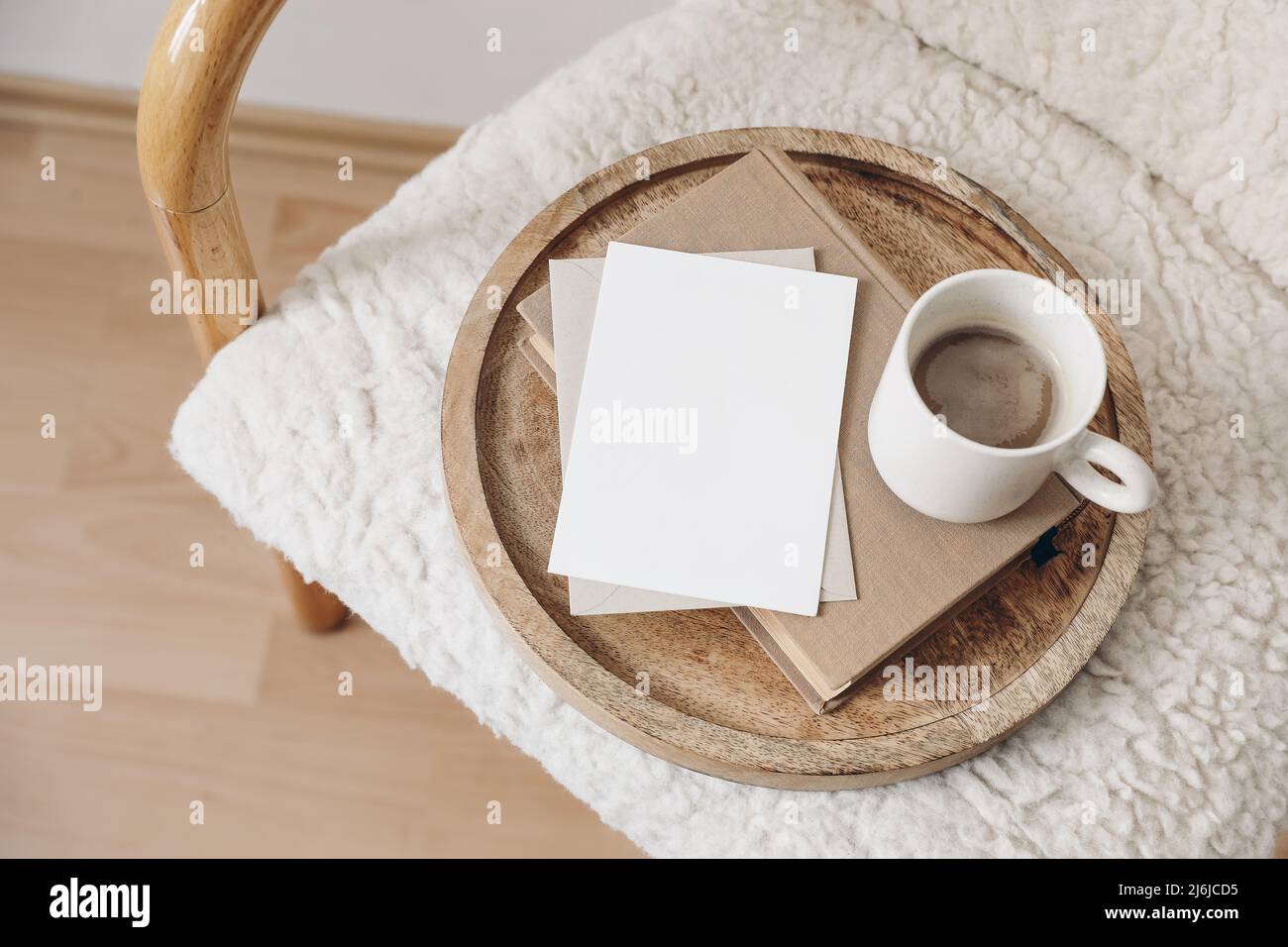 Boho breakfast still life scene. Blank greeting card, invitation. Book, cup of coffee. Wooden tray. Stationery mock-up. Elegant wooden chair, trendy Stock Photo