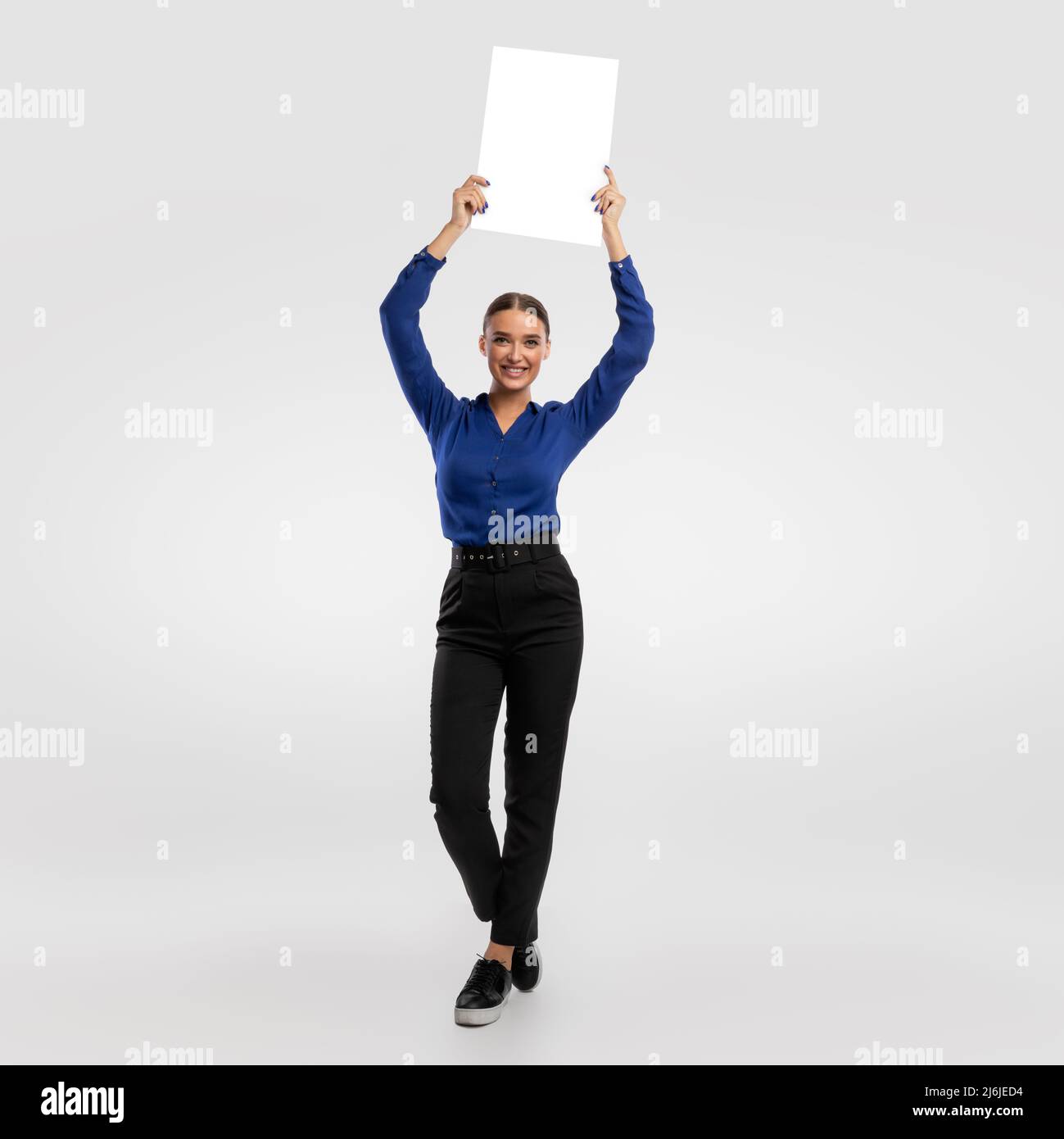 Businesswoman holding blank white advertising billboard at studio Stock Photo