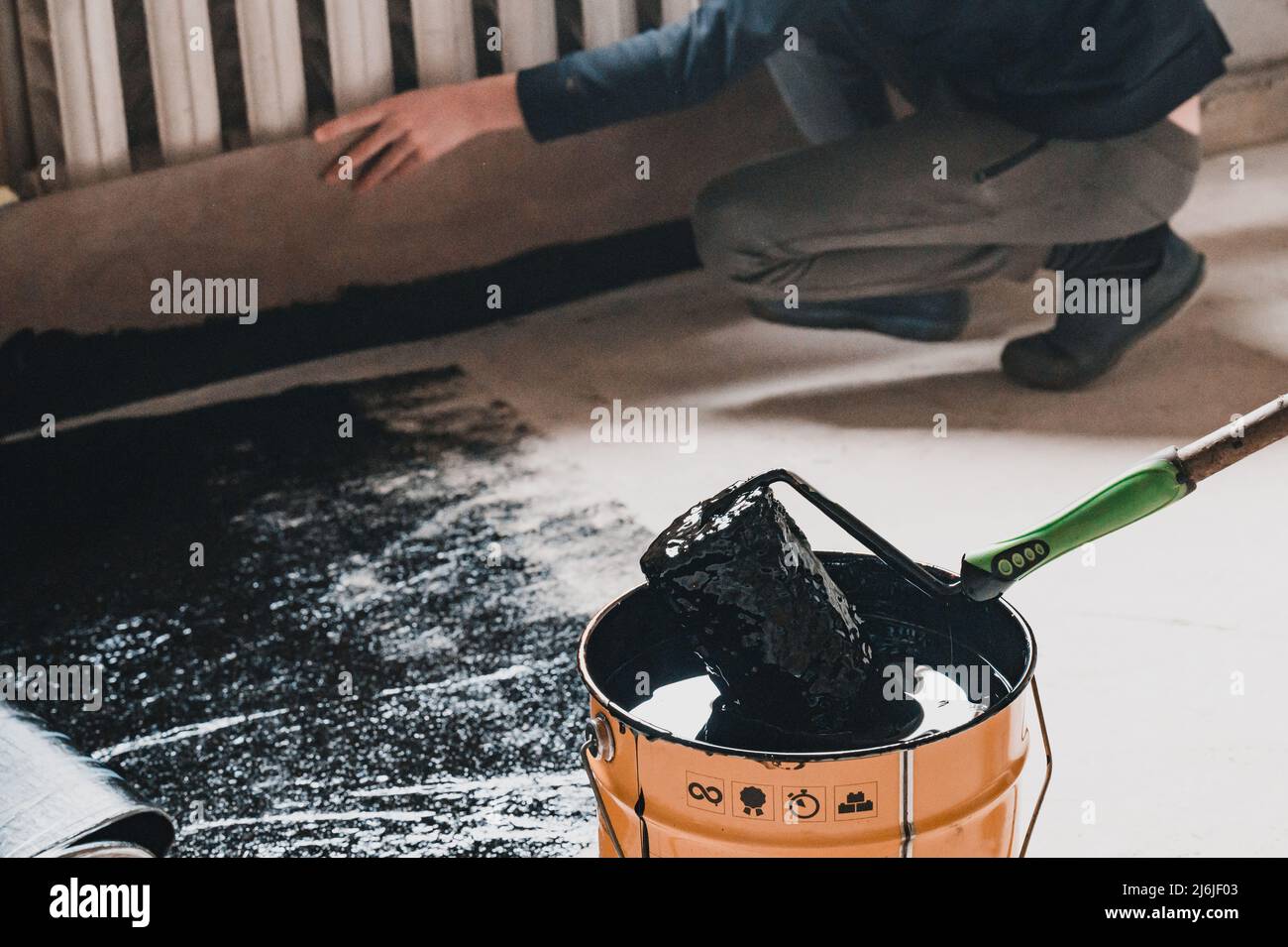 Applying hot resin to the floor for waterproofing, roller and bucket of