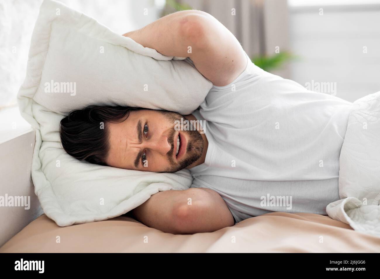 Young man in bed covering head with pillow Stock Photo Alamy