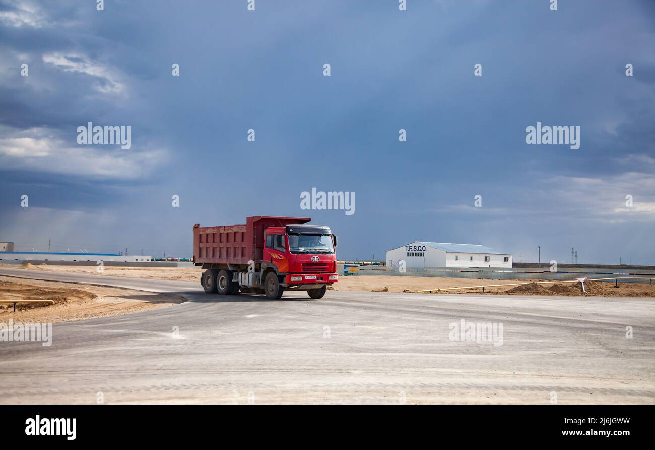 Aktau, Kazakhstan - May 19, 2012. Developing of free economic zone. Red truck FAW on road, and industrial building of T.E.S.C.O. company. Beautiful st Stock Photo