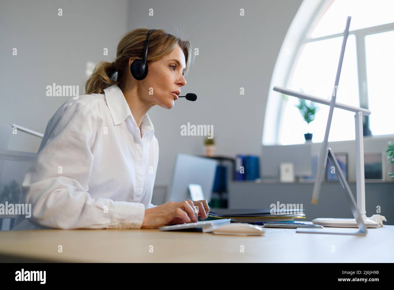 Business woman helpline operator in headset working at computer Stock Photo