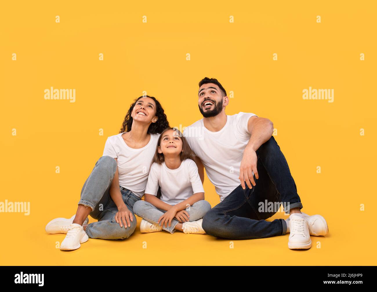 Positive Arabic Family Sitting Looking Up Posing Over Yellow Background