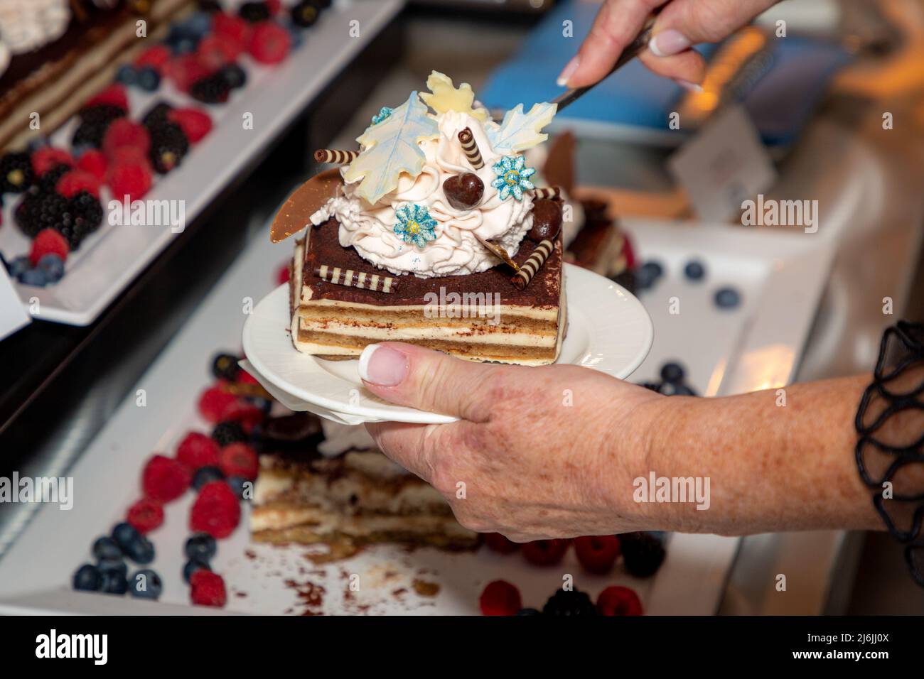 Woman dishing up a piece of layer cake at a buffet dinner party Stock Photo