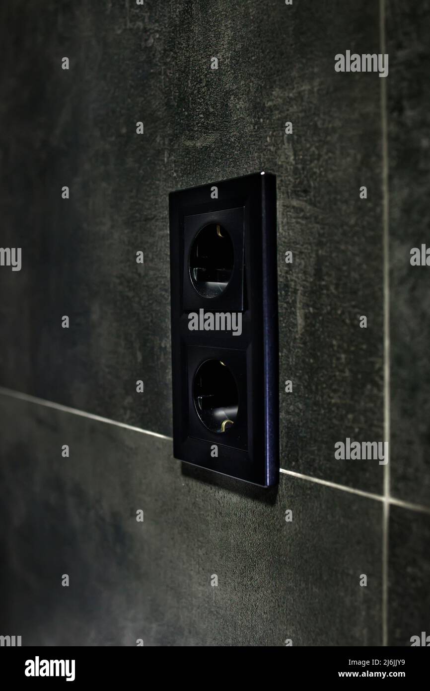 New black rosette on a ceramic tile of black color. Electrical outlet ...