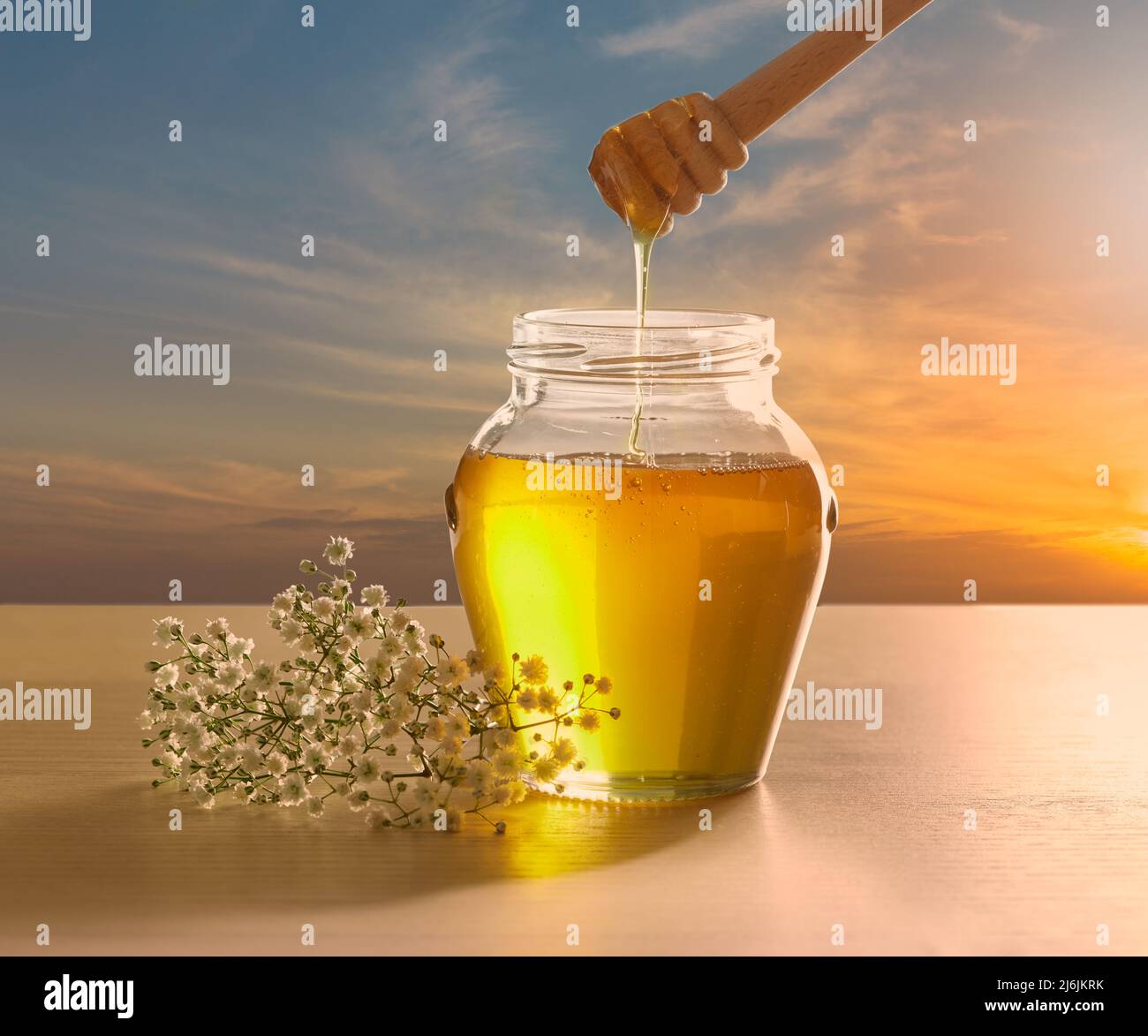 Fresh Honey in glass jar with dipper and sky background Stock Photo