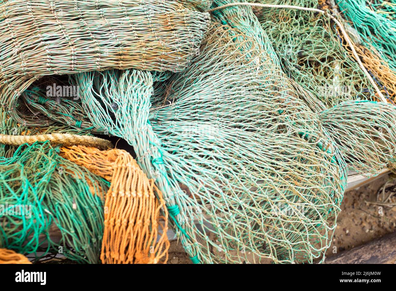A tangle of discarded green and orange fishing nets in the harbour of West Mersea, Mersea Island, Essex United Kingdom Stock Photo
