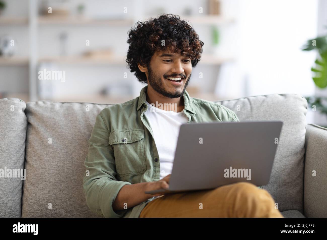 relaxed dark-skinned guy using notebook at home Stock Photo