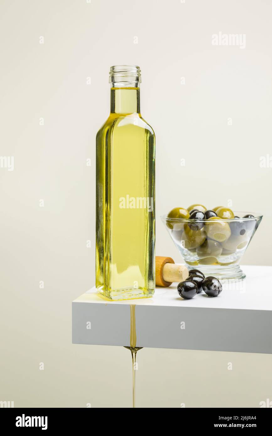 Olive oil bottle with olives on shelf Stock Photo