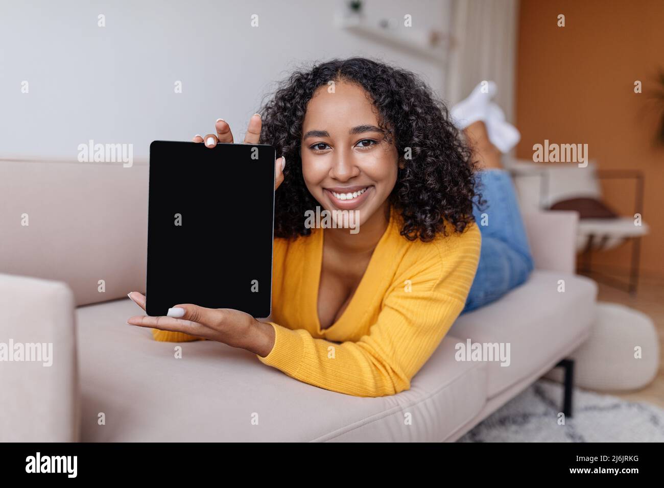 Happy young African American woman showing tablet computer with blank ...