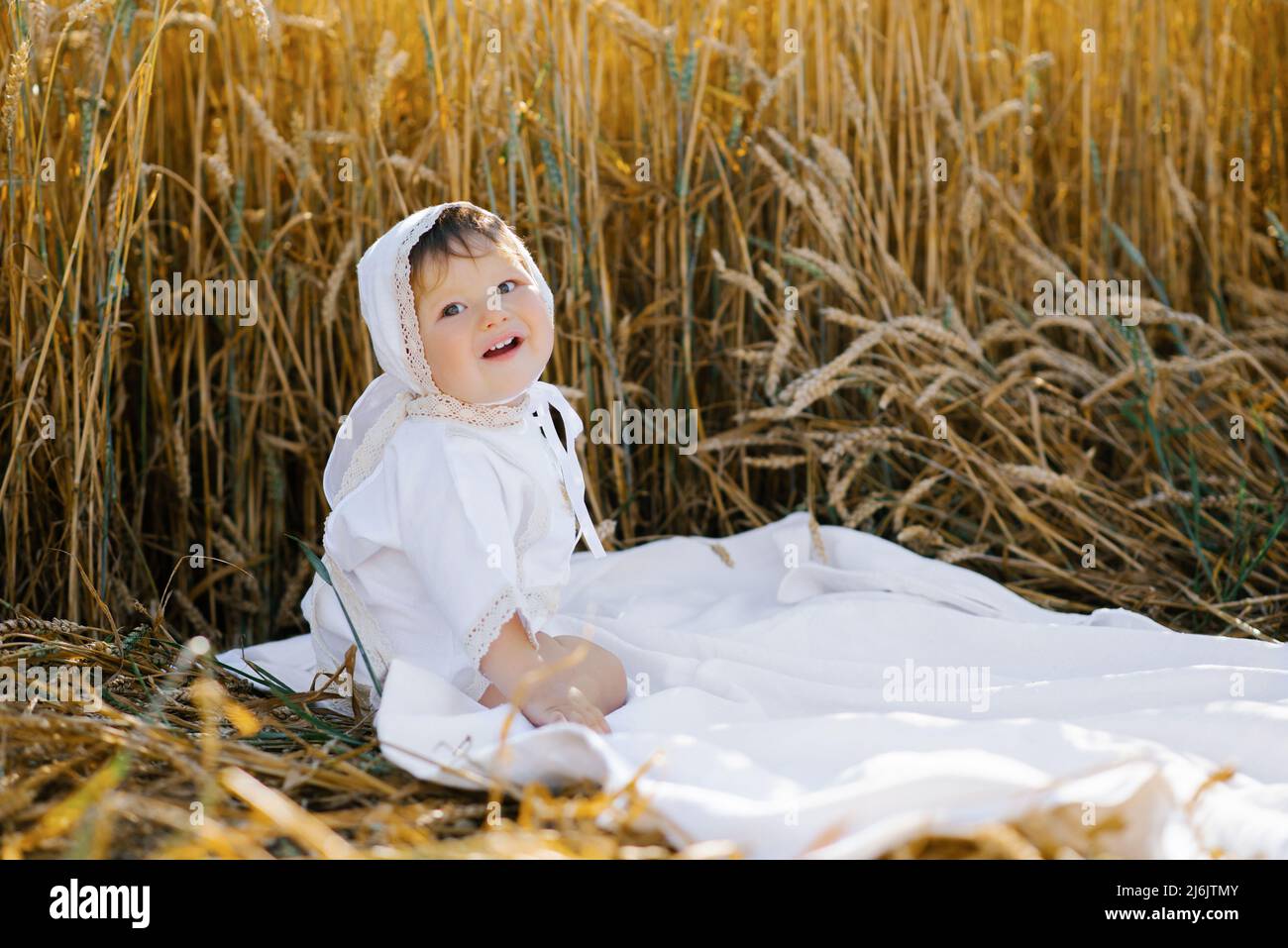 Sweet eightmonthold baby boy sitting on a blanket in a field and