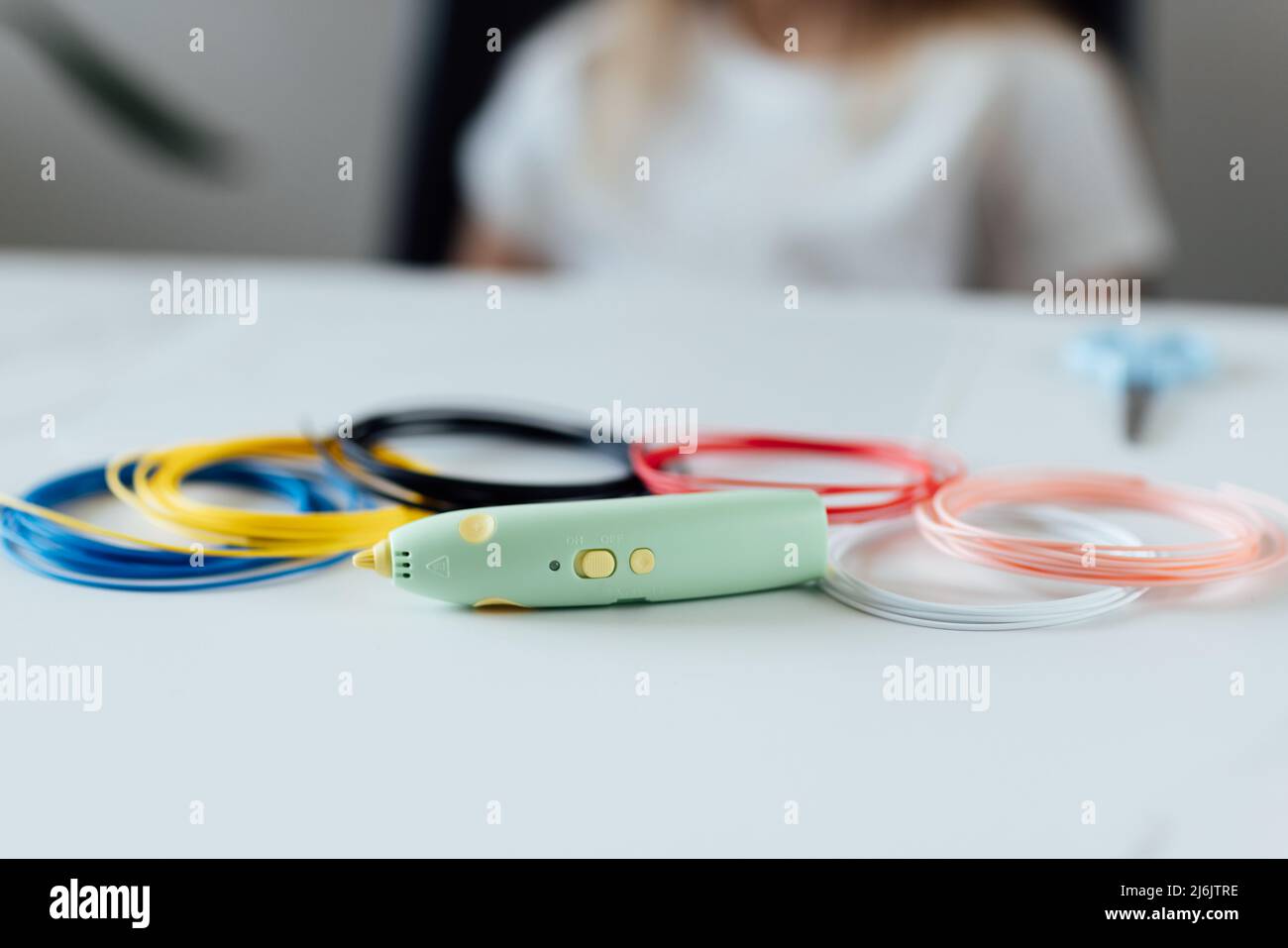 3d pen with a green handle lying on white table. STEM educational toy for kids at home and school. Play and study Stock Photo