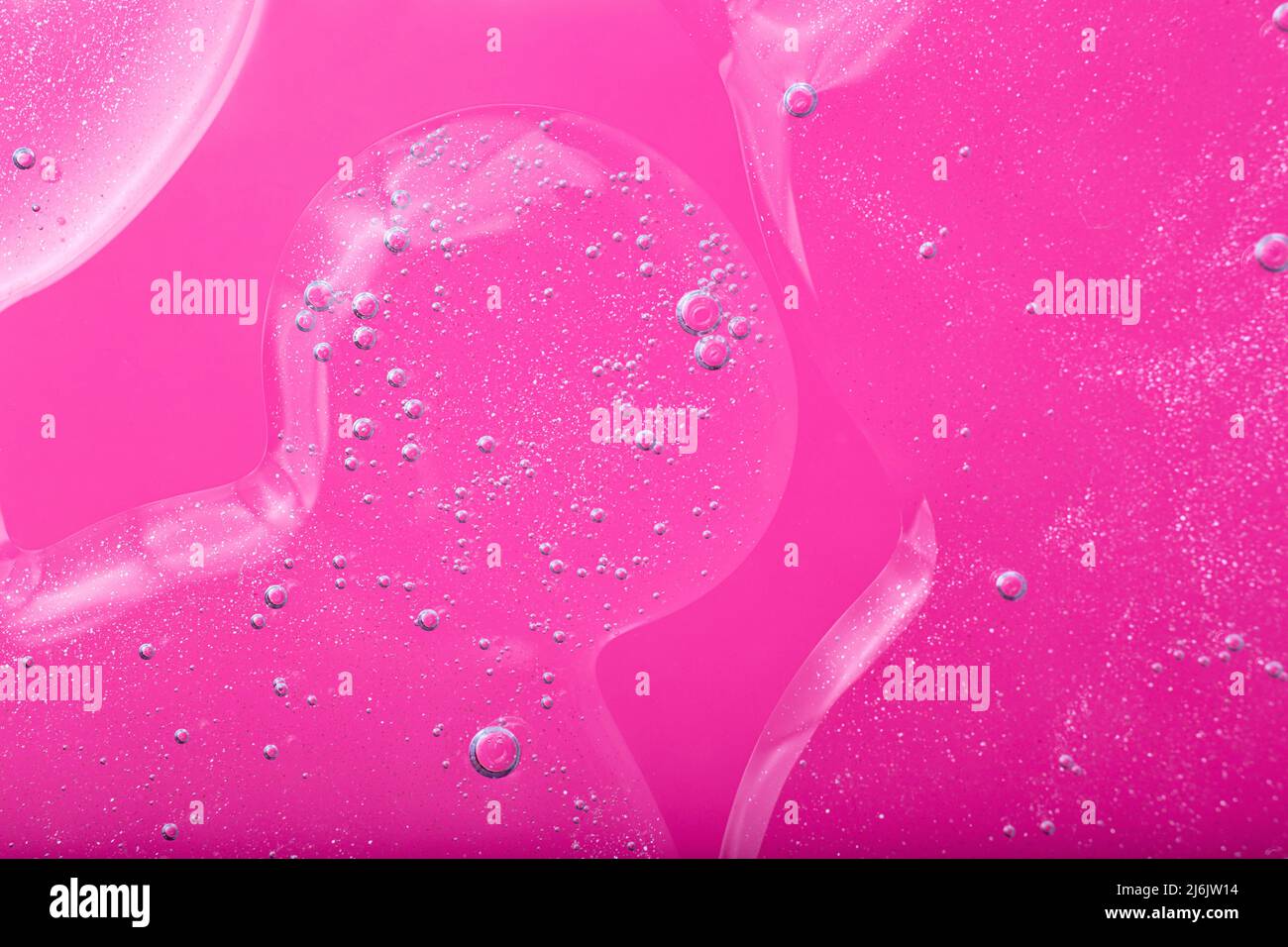 Top view of liquid cosmetics gel with bubbly structure on pink