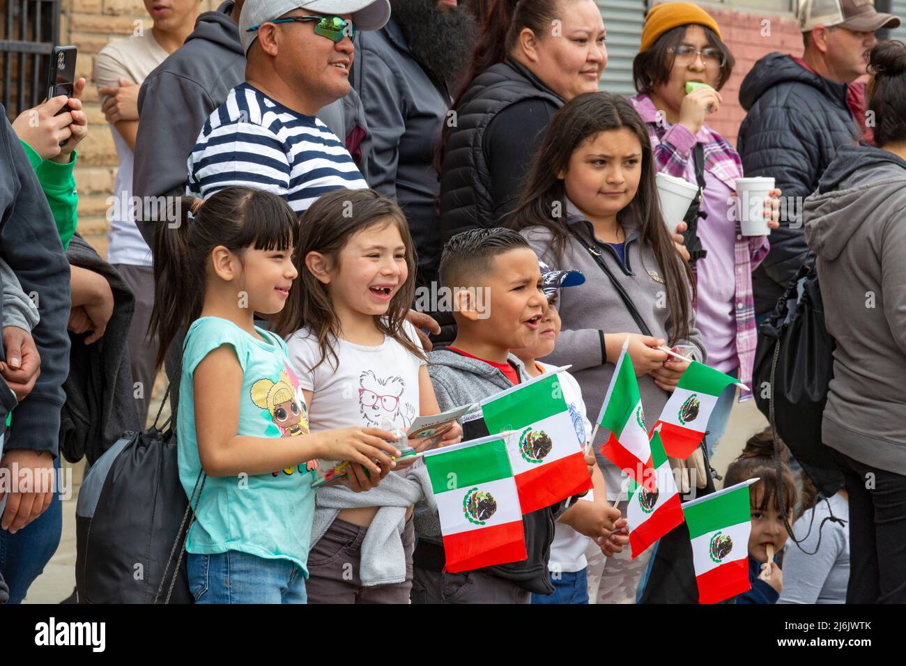 Detroit, Michigan USA - 1 May 2022 - Children hold Mexican flags as they watch the Cinco de Mayo parade in Detroit's Mexican-American neighborhood. Thousands watched the annual parade, which returned in 2022 after a two-year hiatus due to the pandemic. Cinco de Mayo celebrates a Mexican victory over the French on May 5, 1862. Credit: Jim West/Alamy Live News Stock Photo