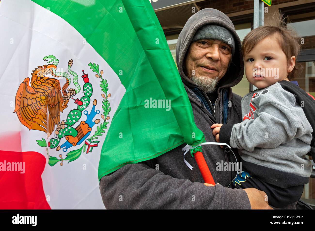 Detroit, Michigan USA - 1 May 2022 - A man and a small child watch the Cinco de Mayo parade in Detroit's Mexican-American neighborhood. Thousands lined the street for the annual parade, which returned in 2022 after a two-year hiatus due to the pandemic. Cinco de Mayo celebrates a Mexican victory over the French on May 5, 1862. Credit: Jim West/Alamy Live News Stock Photo
