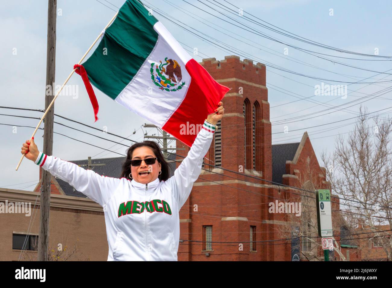 Detroit, Michigan USA - 1 May 2022 - A woman waves a Mexican flag during the Cinco de Mayo parade in Detroit's Mexican-American neighborhood. The annual parade returned in 2022 after a two-year hiatus due to the pandemic. Cinco de Mayo celebrates a Mexican victory over the French on May 5, 1862. Credit: Jim West/Alamy Live News Stock Photo