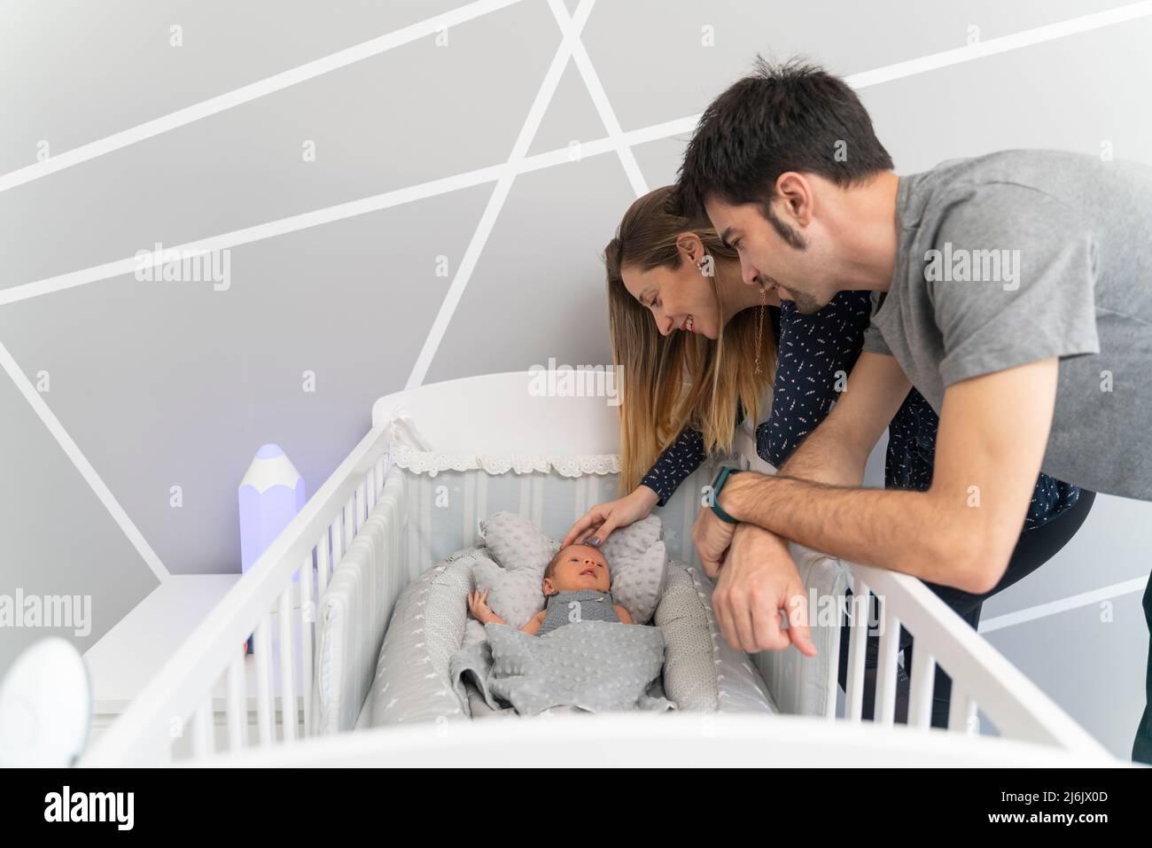 A couple of parents looking their newborn baby in the cradle Stock Photo