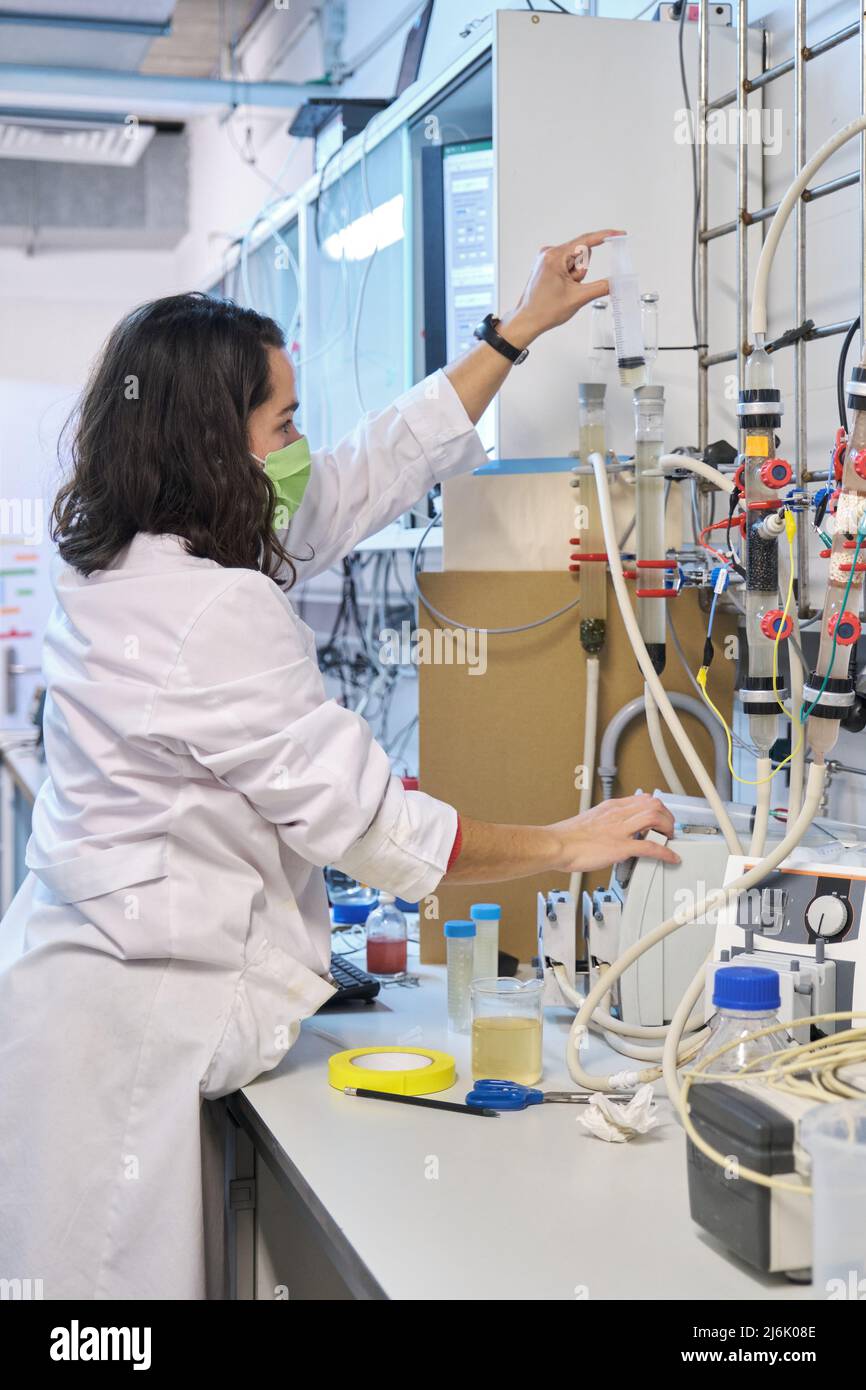 Researcher inoculating a Fluidized Bed Reactor with waste water in a laboratory. Stock Photo