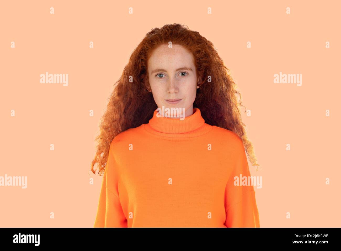 Pensive redhaired girl isolated on a orange background Stock Photo