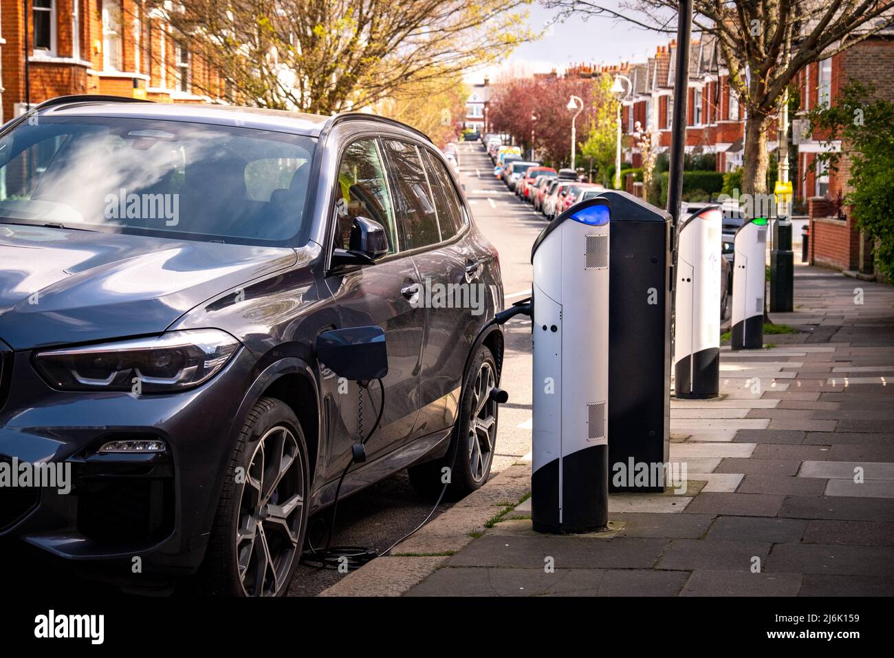 An electric car on-street charging on residential street Stock Photo