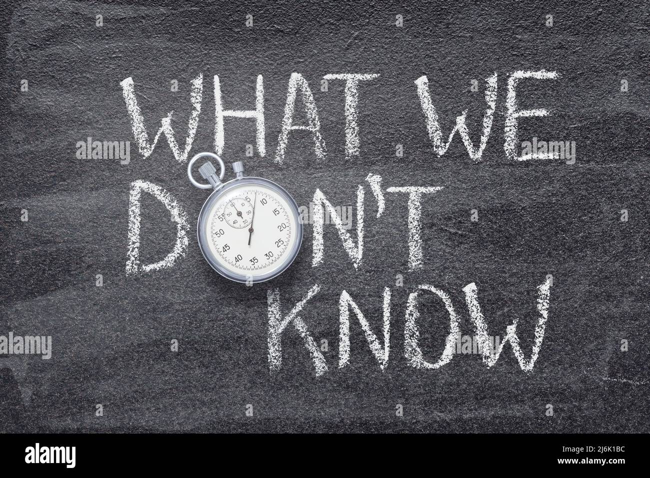 what we don’t know phrase written on chalkboard with vintage precise stopwatch Stock Photo