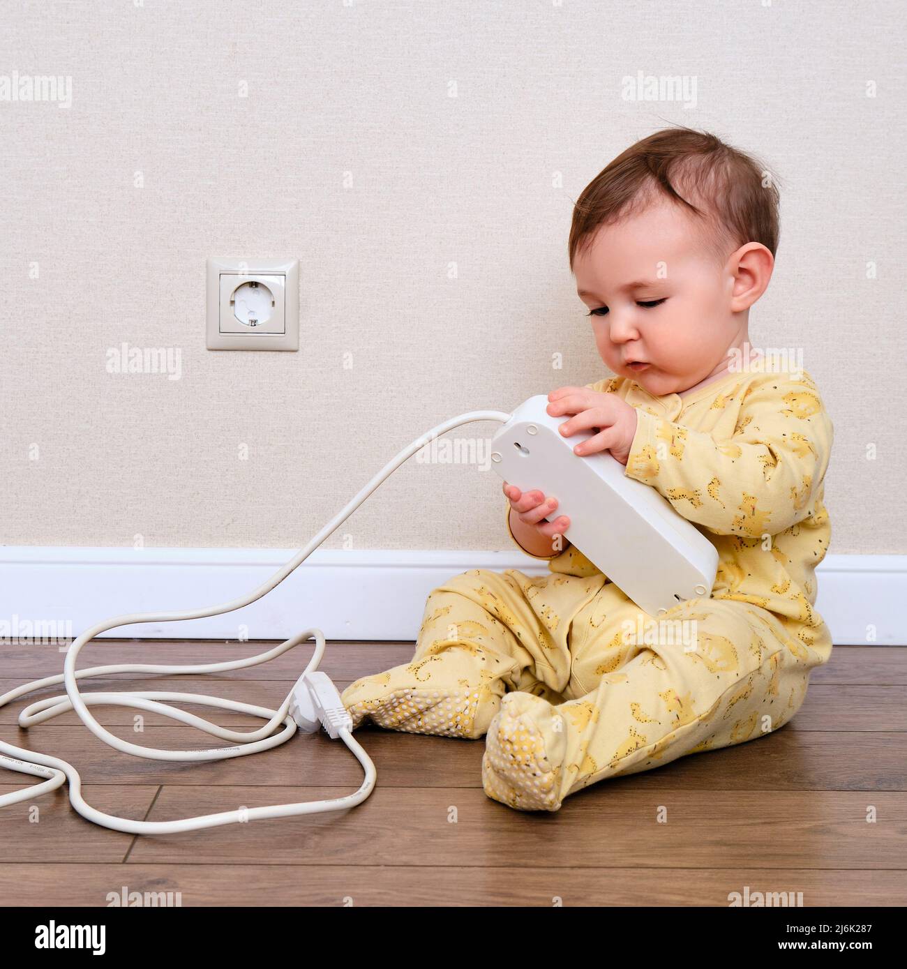 Toddler baby boy plays with electric wires while sitting on the floor