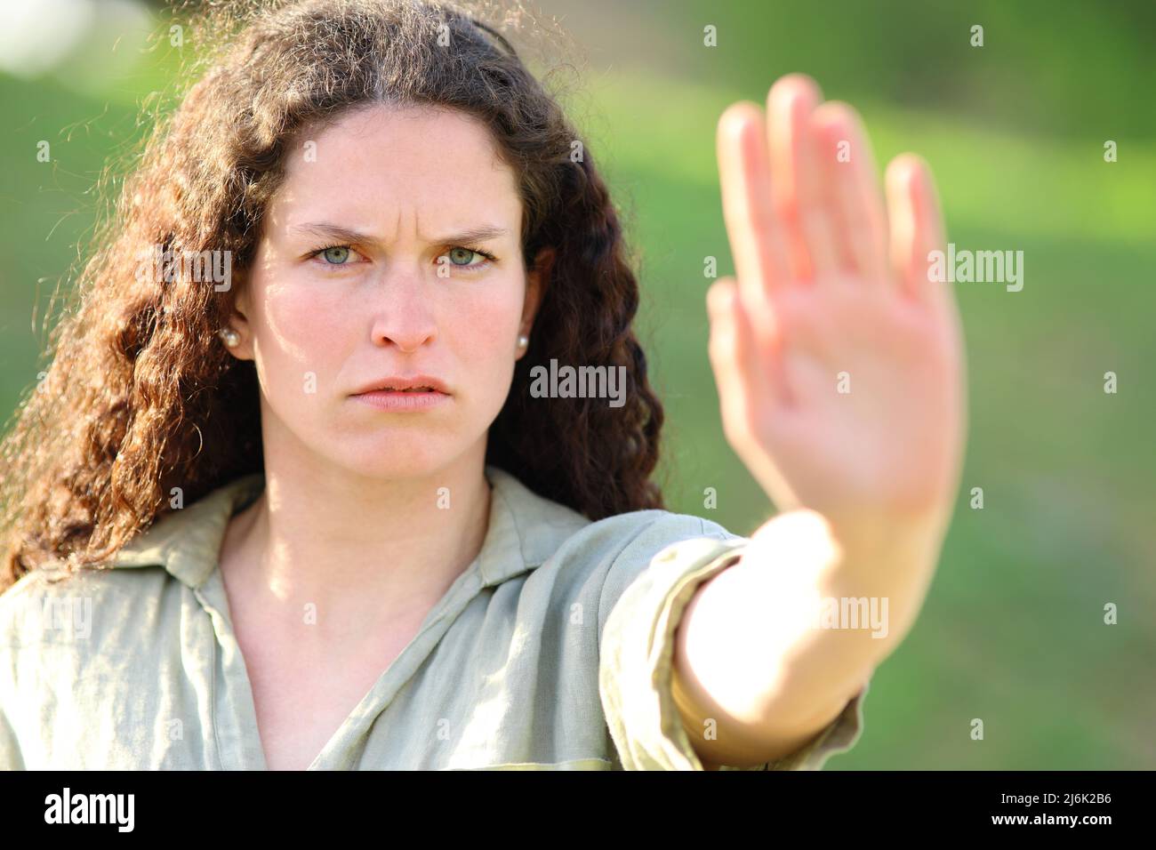 Front view portrait of an angry woman gesturing stop with palm in a park Stock Photo