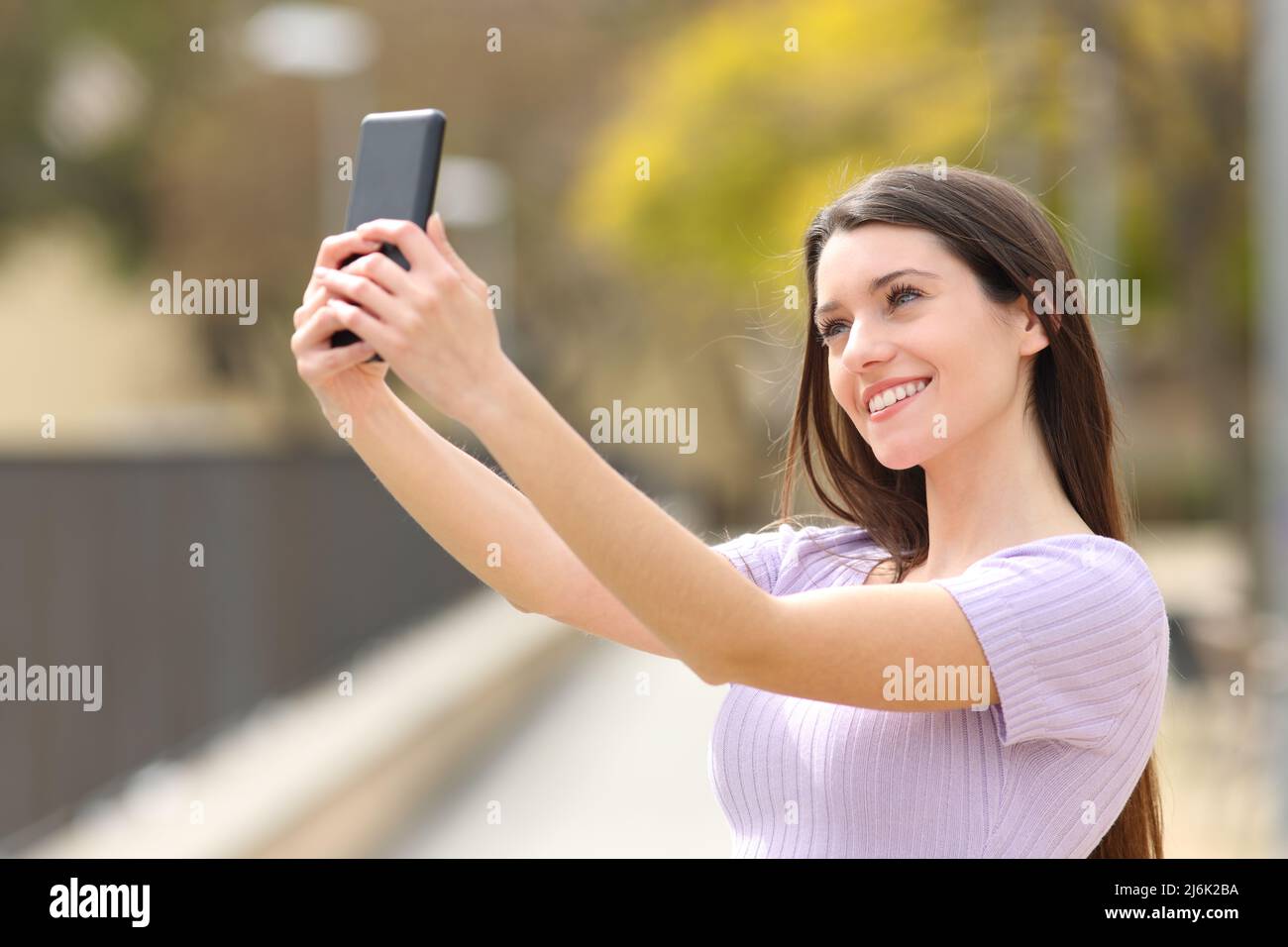 Happy teen taking selfie with smart phone in a park Stock Photo