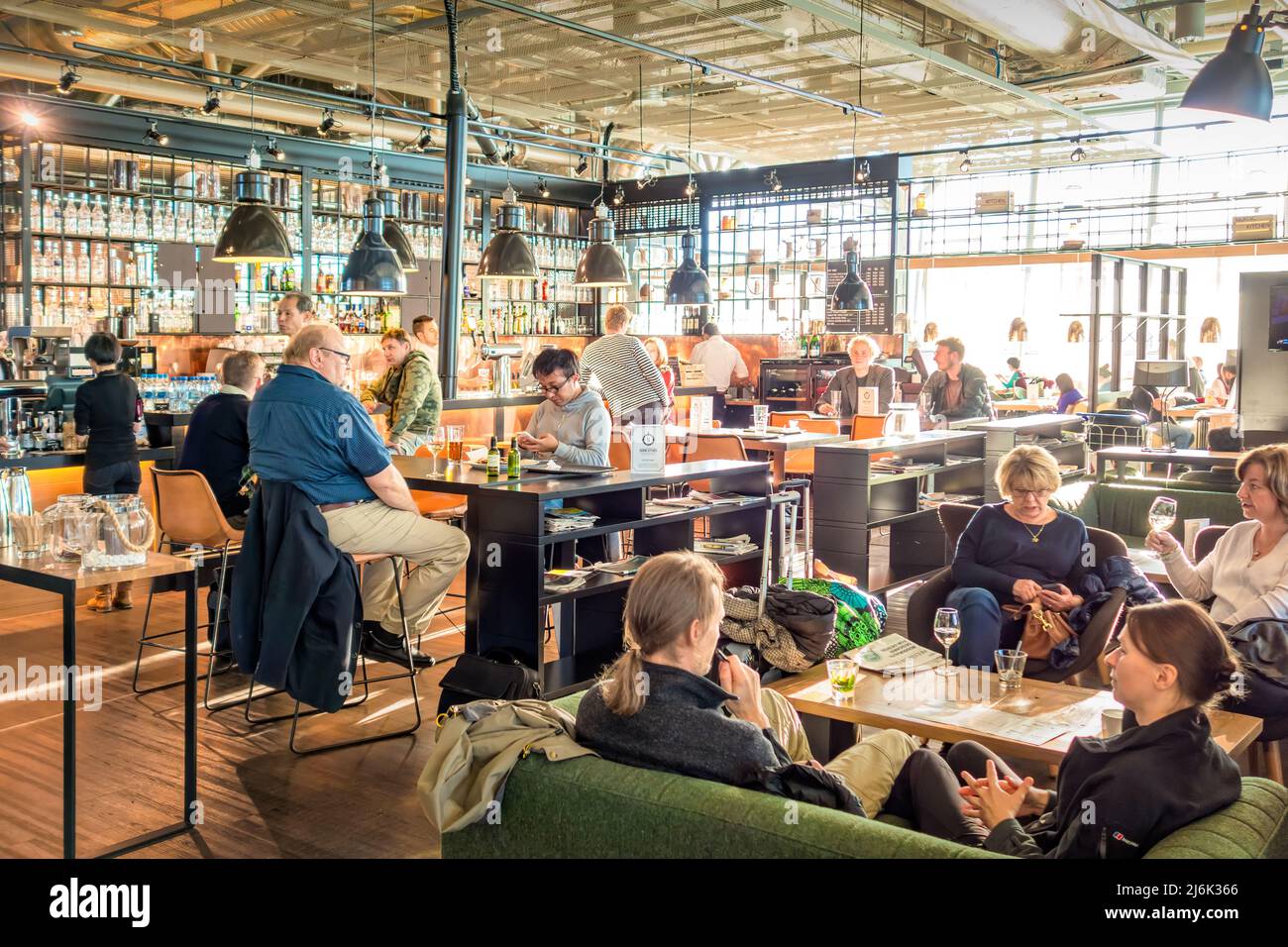 People relax at a restaurant bar at Helsinki Vantaa International Airport Finland in Helsinki, Finland on a sunny day. Stock Photo