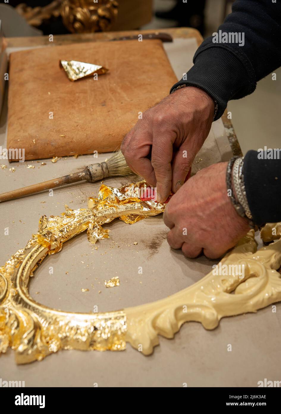 Application of gold leaf to a frame. Gilding process technique.. Stock Photo