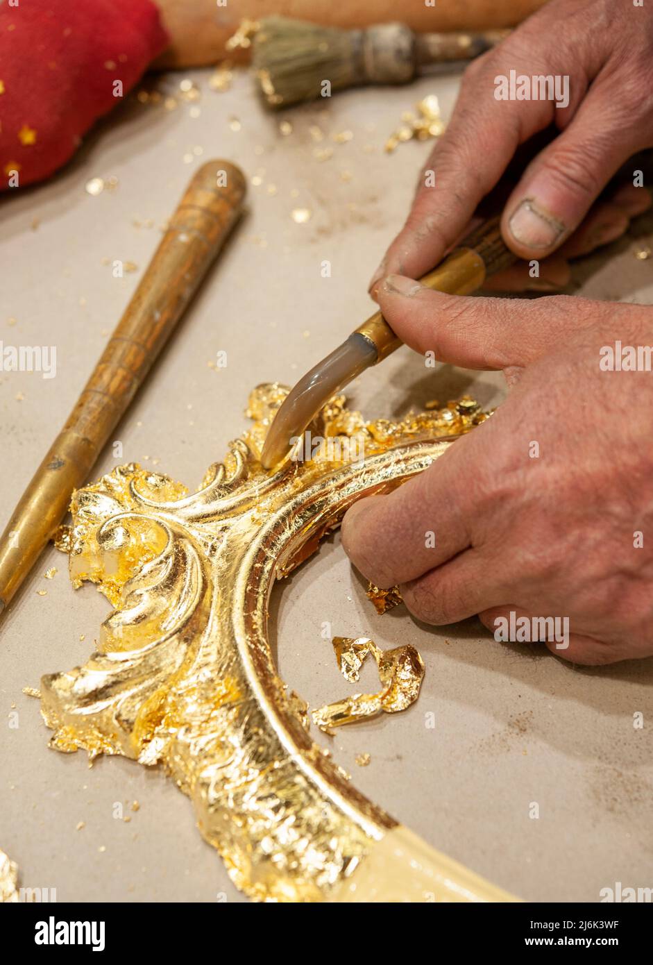 Gilded frame ready for burnishing with an agate stone tool. Gilding process technique.. Stock Photo