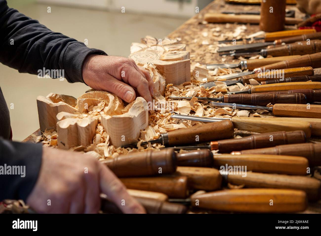 Master woodcarver at work. Wood shavings, gouges and chisels on the workbench. Stock Photo