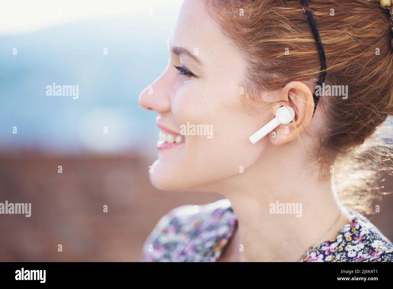 Happy young redhead woman calling by hands free device closeup, profile view Stock Photo