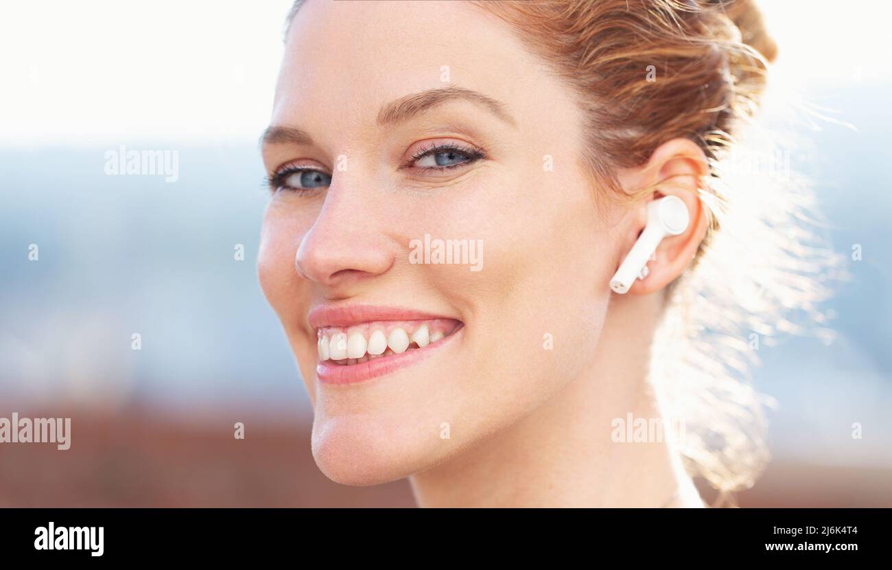 Happy young redhead woman calling by hands free device closeup, looking into camera Stock Photo